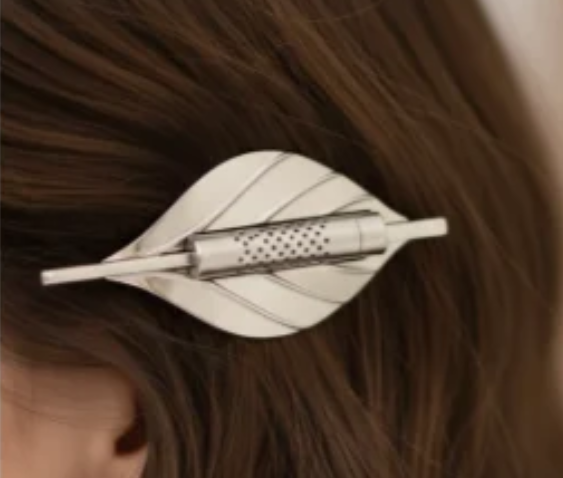Pince à cheveux parfumable Osmélya en forme de feuille, en acier inoxydable argenté, portée dans les cheveux avec capsule textile rechargeable intégrée